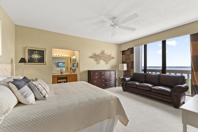 carpeted bedroom with expansive windows, a textured ceiling, a water view, and ceiling fan