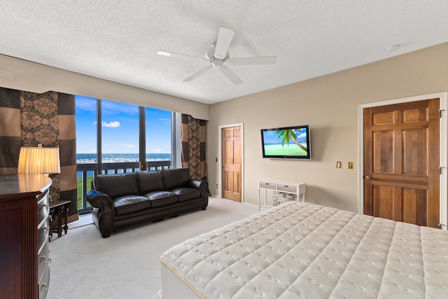 bedroom with ceiling fan, light colored carpet, and a textured ceiling