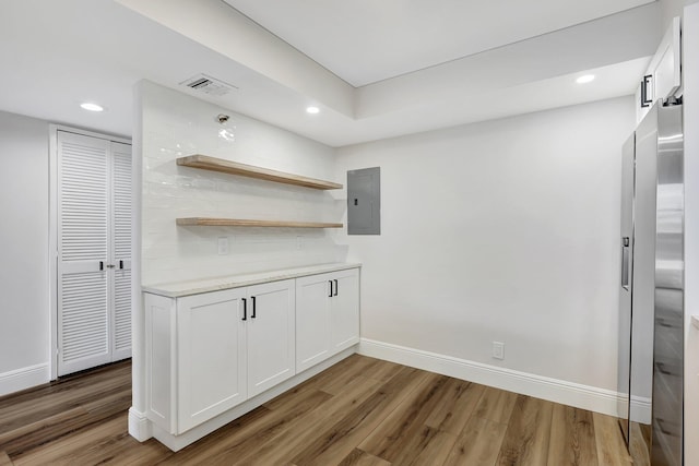 kitchen with white cabinets, light stone countertops, dark wood-type flooring, and electric panel