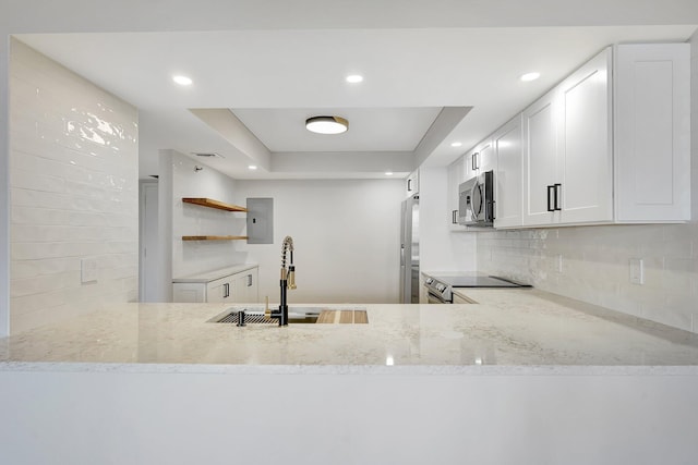 kitchen with light stone countertops, white cabinetry, sink, stainless steel appliances, and a raised ceiling