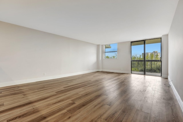 unfurnished room featuring floor to ceiling windows and wood-type flooring