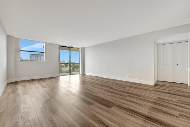 unfurnished room with expansive windows and light hardwood / wood-style floors