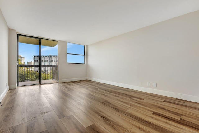 unfurnished room featuring expansive windows and wood-type flooring