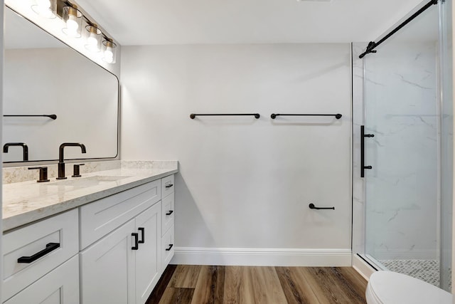 bathroom featuring a shower with door, vanity, wood-type flooring, and toilet