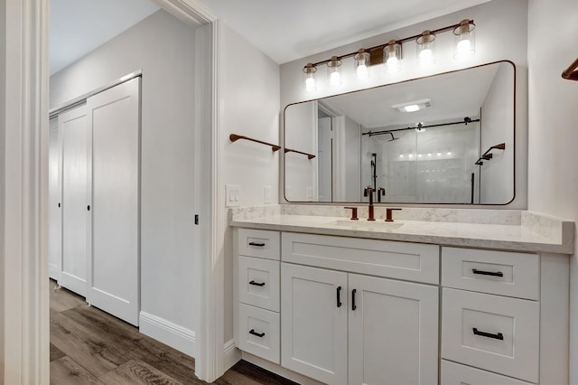 bathroom with hardwood / wood-style floors, vanity, and a shower with shower door