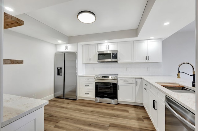 kitchen featuring white cabinets, appliances with stainless steel finishes, light hardwood / wood-style flooring, and sink