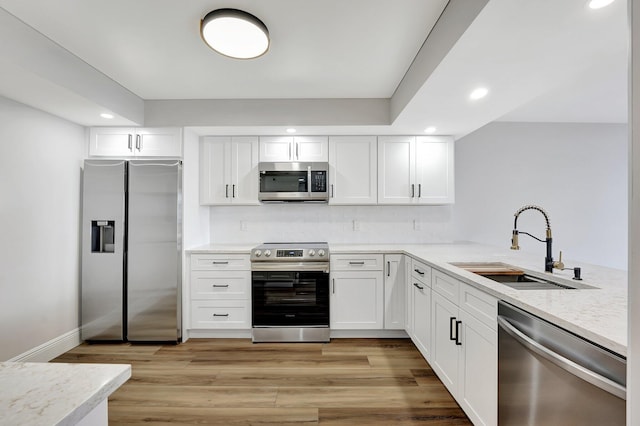 kitchen featuring stainless steel appliances, white cabinetry, light hardwood / wood-style floors, and sink