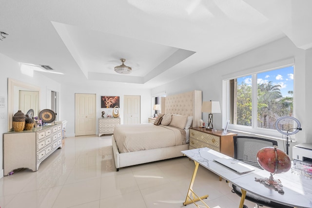 tiled bedroom featuring ceiling fan and a tray ceiling