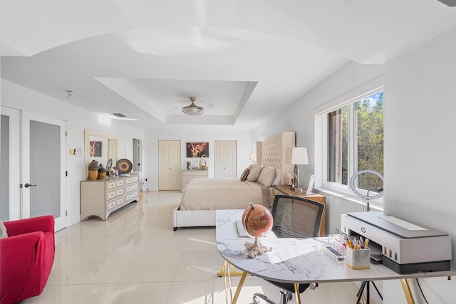 tiled bedroom featuring ceiling fan and a raised ceiling