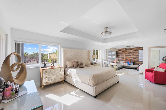 bedroom with light tile patterned floors, a raised ceiling, a closet, and ceiling fan