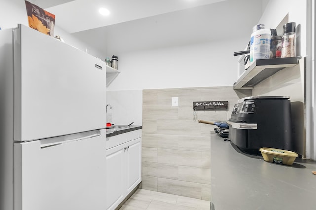 kitchen with white cabinets, white fridge, and light tile patterned floors