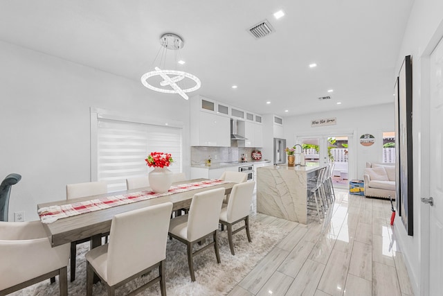 dining space with french doors, a chandelier, and light hardwood / wood-style flooring