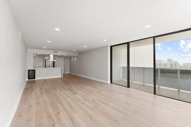 unfurnished living room featuring a wall of windows and light wood-type flooring