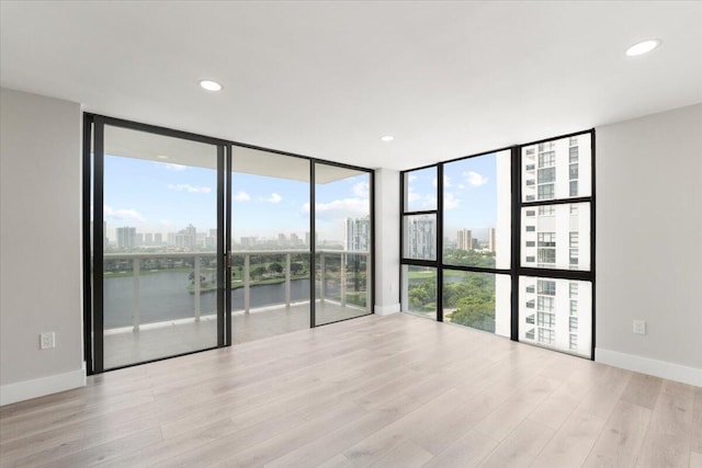 empty room featuring light hardwood / wood-style floors, expansive windows, and a water view