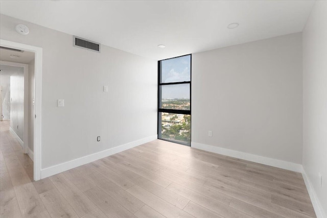 empty room with light hardwood / wood-style floors and expansive windows