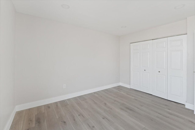 unfurnished bedroom with a closet and light hardwood / wood-style floors