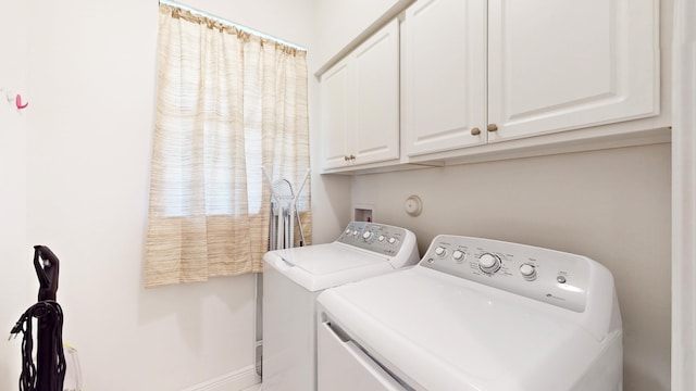 clothes washing area with cabinets and independent washer and dryer