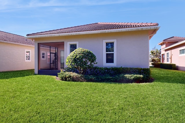 back of house featuring a sunroom and a lawn