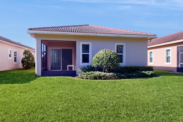 rear view of property with a sunroom and a lawn