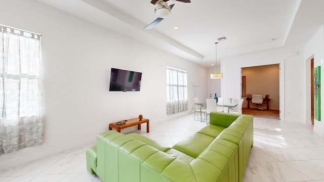 living room featuring a tray ceiling and ceiling fan