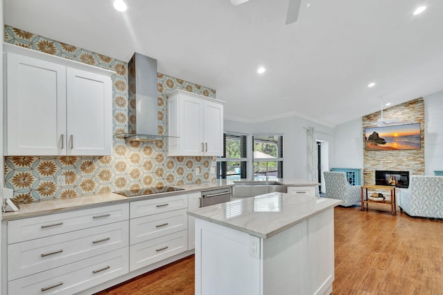 kitchen with white cabinetry, dishwasher, wall chimney exhaust hood, black electric cooktop, and a fireplace