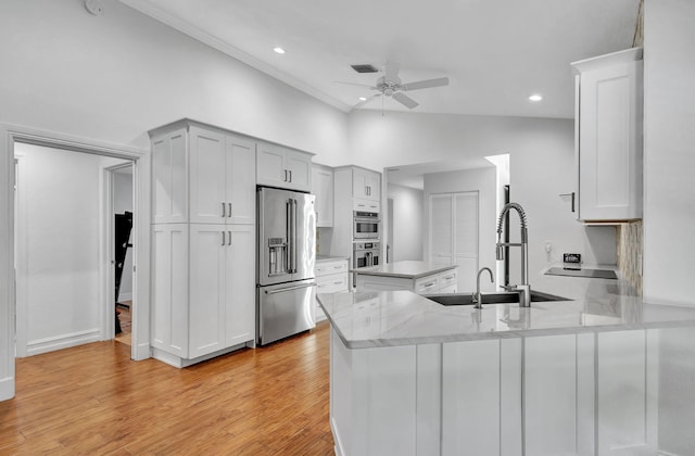 kitchen with white cabinets, vaulted ceiling, light hardwood / wood-style flooring, high quality fridge, and kitchen peninsula