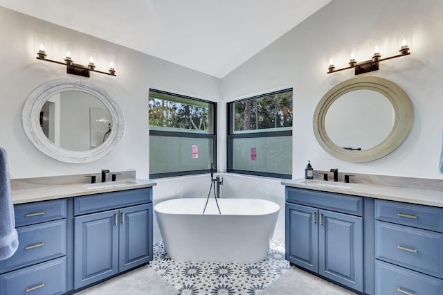 bathroom featuring a washtub, lofted ceiling, and vanity