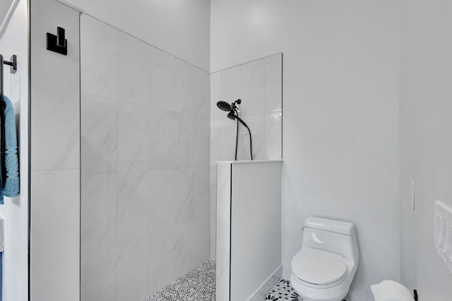 bathroom with tiled shower, tile patterned floors, and toilet