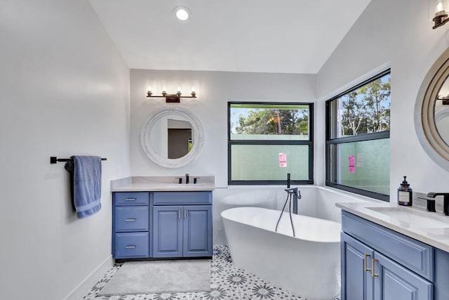 bathroom with tile patterned floors, vanity, lofted ceiling, and a tub to relax in