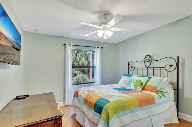 bedroom with a textured ceiling, light hardwood / wood-style floors, and ceiling fan