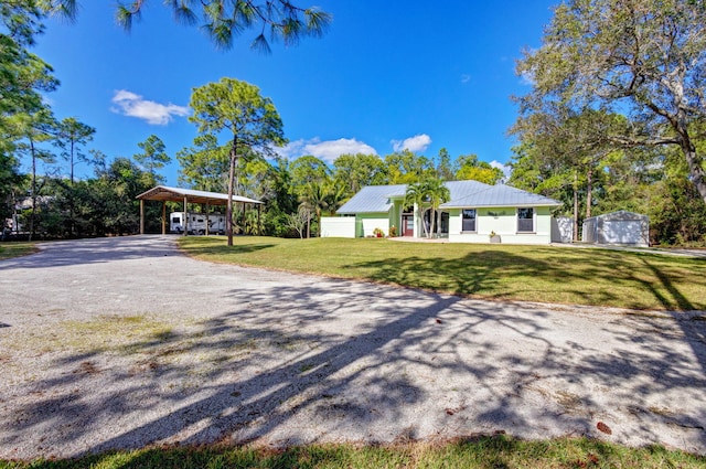 single story home featuring a carport, a storage unit, and a front yard