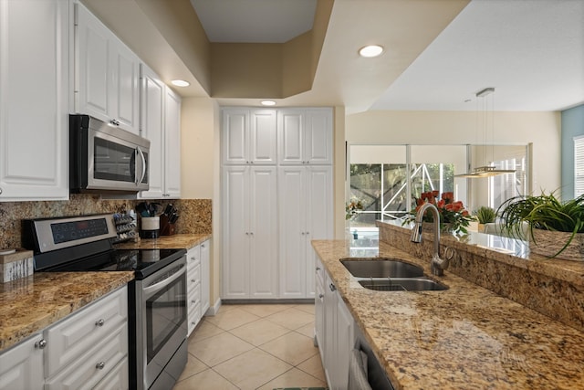 kitchen with sink, hanging light fixtures, stainless steel appliances, light stone counters, and white cabinets