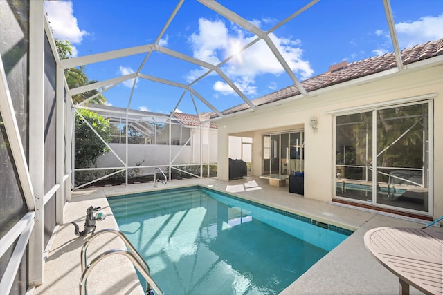 view of pool with a patio area and glass enclosure