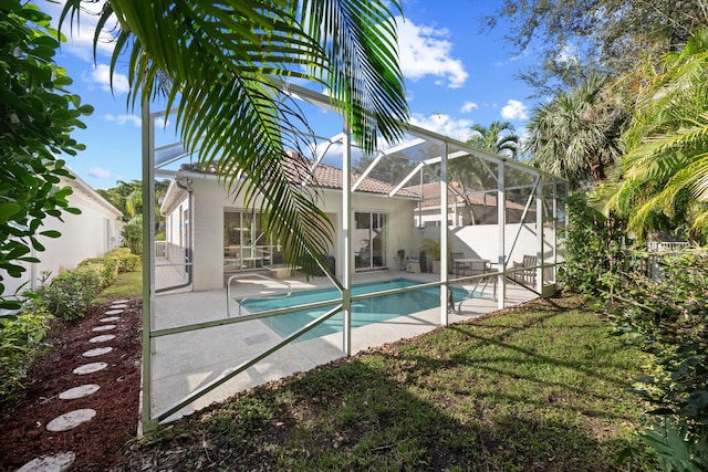 view of swimming pool with a yard, glass enclosure, and a patio area