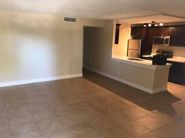 kitchen with kitchen peninsula, appliances with stainless steel finishes, light tile patterned floors, and sink