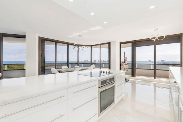 kitchen with white cabinets, black electric cooktop, oven, and decorative light fixtures