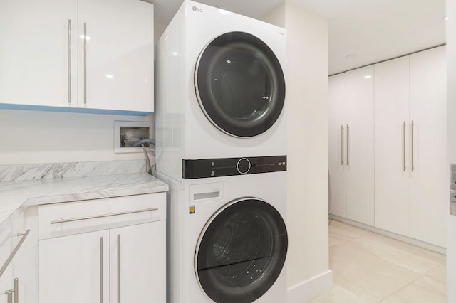 clothes washing area featuring cabinets, light tile patterned floors, and stacked washer / drying machine