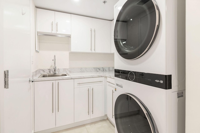 washroom featuring cabinets, light tile patterned floors, stacked washer and clothes dryer, and sink