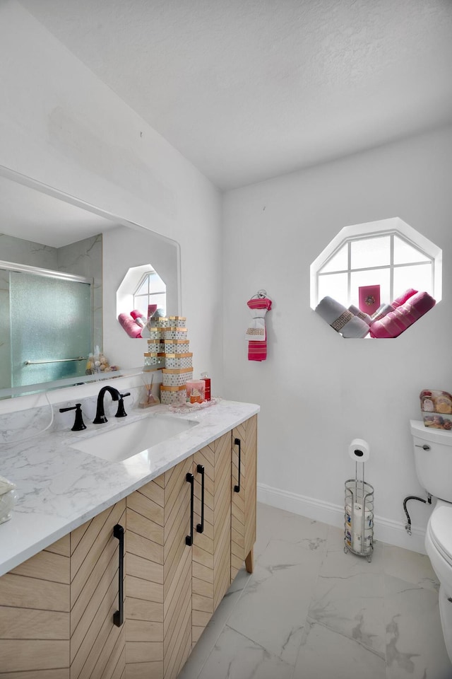 bathroom featuring an enclosed shower, vanity, and toilet