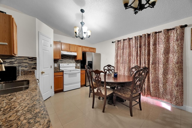 dining space with light tile patterned flooring, vaulted ceiling, a notable chandelier, and sink