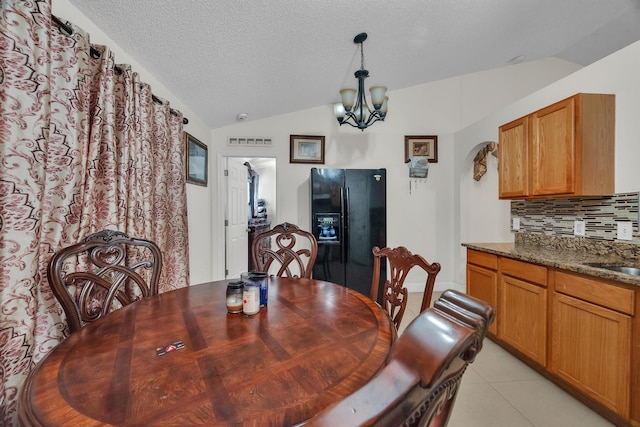 tiled dining room featuring a chandelier, a textured ceiling, vaulted ceiling, and sink