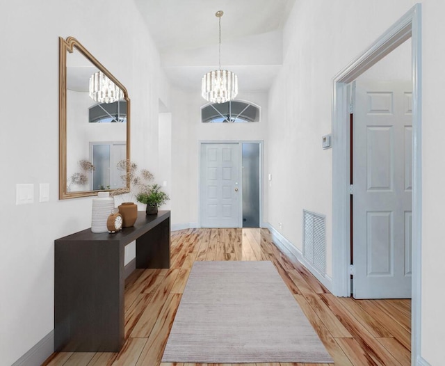 entryway featuring light hardwood / wood-style floors, high vaulted ceiling, and a chandelier