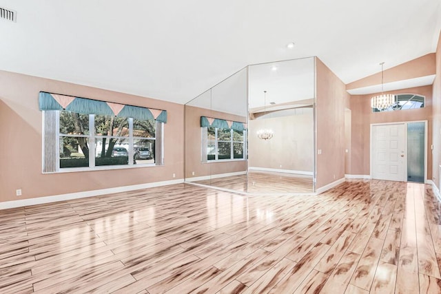 unfurnished living room with a notable chandelier, high vaulted ceiling, and light hardwood / wood-style flooring