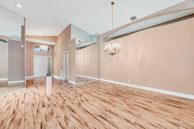 entryway with a chandelier, high vaulted ceiling, and light hardwood / wood-style floors