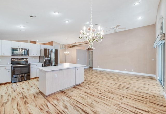 kitchen with white cabinets, appliances with stainless steel finishes, decorative light fixtures, a kitchen island, and light wood-type flooring