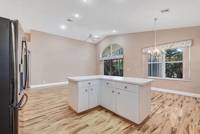 kitchen featuring lofted ceiling, kitchen peninsula, light hardwood / wood-style floors, white cabinetry, and stainless steel refrigerator