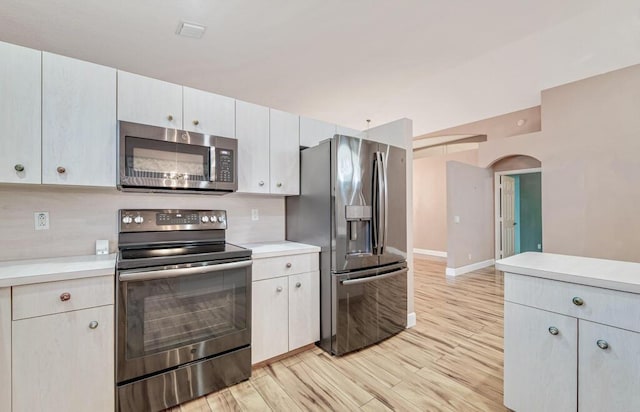 kitchen featuring tasteful backsplash, light hardwood / wood-style flooring, white cabinets, and appliances with stainless steel finishes