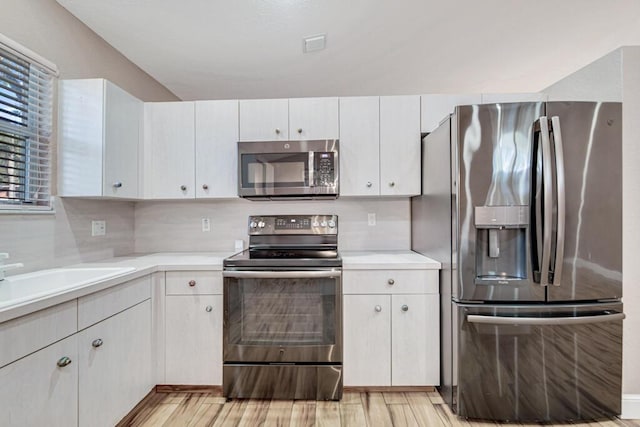 kitchen with light hardwood / wood-style floors, white cabinetry, and appliances with stainless steel finishes