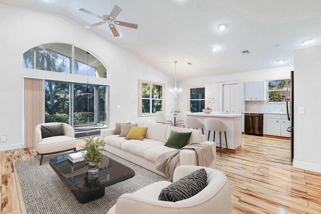 living room with high vaulted ceiling, ceiling fan with notable chandelier, and light wood-type flooring