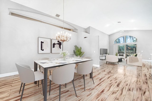 dining room with ceiling fan with notable chandelier, light wood-type flooring, and vaulted ceiling